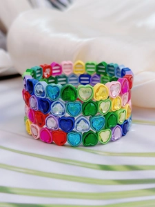 Primer plano de pulseras elásticas de cristal de corazón coloridas en tela suave