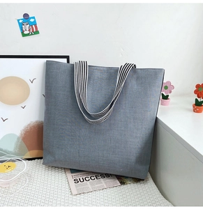 Macro shot of grey canvas tote bag with woven texture and black and white striped handles