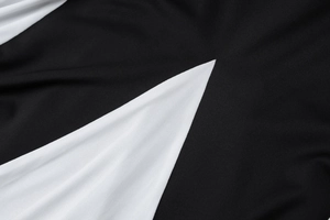 Gros plan des coutures contrastées sur tissu noir et blanc montrant la texture de qualité