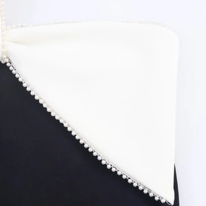 Macro detail of high-quality pearl beaded trim on black and white midi dress edges