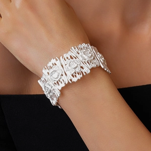 Detailed close-up of matte silver square floral hollow link bracelet on model's wrist