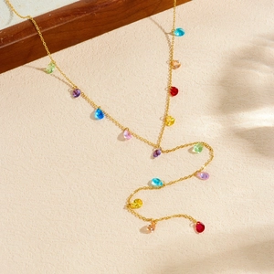 Collier chaîne dorée avec pendentifs colorés en forme de larme sur fond beige texturé