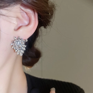 Close-up of sparkling leaf-shaped silver earrings with rhinestones on model's ear