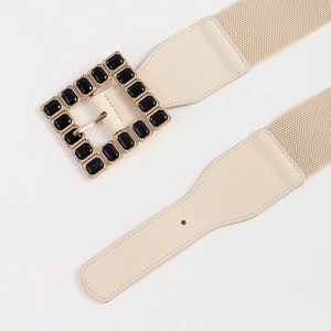 Detail of beige elastic waist belt featuring a gold square buckle with black faceted gems