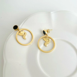 Elegant gold fox pendant earrings with matte texture on a clean white ceramic base