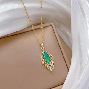 Close-up of a leaf pendant necklace with green and white marquise zircons on silk