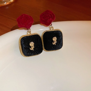 Detail of red and black flocked rose earrings with gold floral relief and vintage finish
