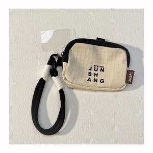 Close-up of a beige plaid mini pouch with a black hand strap and transparent card holder