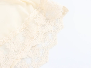 Dettaglio del ricamo in pizzo crema elegante su un abito lungo con scollo a V francese