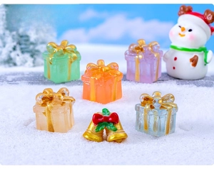 Close-up of colorful resin Christmas gift box miniatures and bells on artificial snow