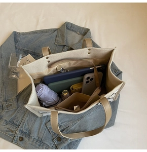 Flat lay of beige canvas tote bag showing interior storage capacity and essentials