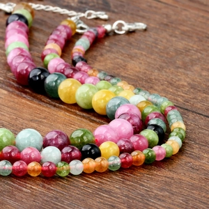 Close-up of vintage multi-color tourmaline beads with silver lobster clasp on wood
