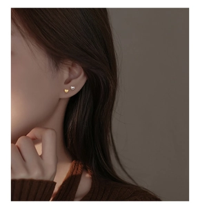 Close-up of minimalist heart-shaped silver earrings in gold and silver finishes