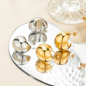 Modern gold and silver chunky teardrop hoop earrings on mirror surface reflection