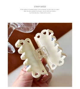 Detail of cream hair claw clip with heart cut-outs and polished resin finish