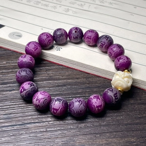 Detailed view of purple embossed beads and a white mythical beast carving on the bracelet