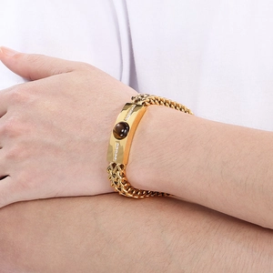 Close-up of men's gold plated steel bracelet featuring tiger eye stone and crystals