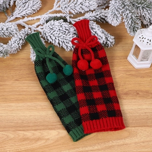 Détail de couvre-bouteilles de Noël en tricot à carreaux avec pompons sur bois