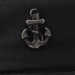 Detailed close-up of a vintage silver metal anchor emblem on black knitted fabric