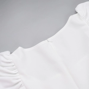 Détail de la fermeture éclair invisible et de la manche bouffante plissée sur robe blanche