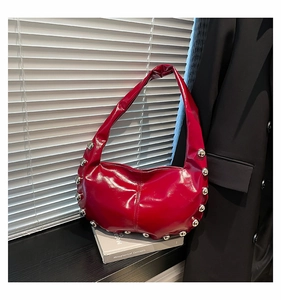 Detail of red patent leather tote bag with silver studs and crescent moon shape