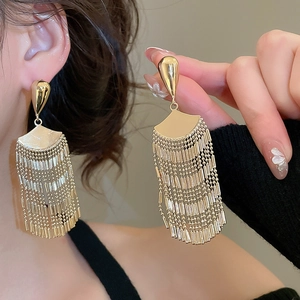 Macro shot of gold fan-shaped tassel earrings showing refined metallic texture and details