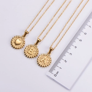 Close-up of 18k gold plated heart and letter pendants showing 1.5cm size on ruler