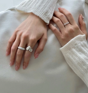 Close-up of stacked 925 sterling silver heart and anchor chain rings on a model