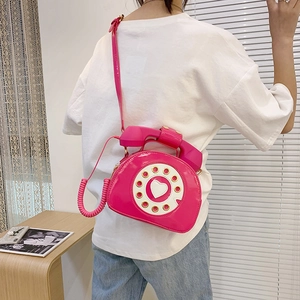 Detail of pink telephone-shaped crossbody bag showing the creative dial and handset handle
