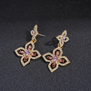 Detailed close-up of gold floral earrings with pink and purple rhinestones