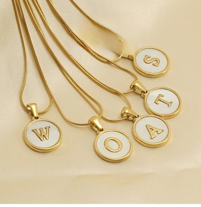 Detail of 18K gold snake chain necklace with round white shell alphabet letter pendants