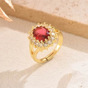 Close-up of elegant gold ring with oval red gemstone and sparkling clear crystal halo