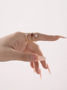 Detailed view of gold triple ring set with pear cut and heart shaped crystals on a hand