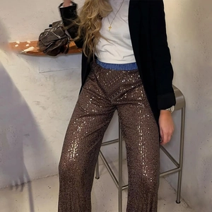 Detailed shot of dark brown sequined trousers styled with a white tee and black blazer