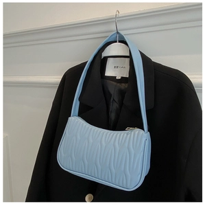 Detail of light blue underarm bag with wavy quilted pattern on black blazer