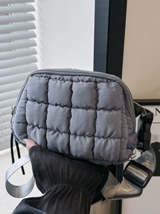Grey quilted puffer waist bag with adjustable strap shown in a bright hand-held close-up