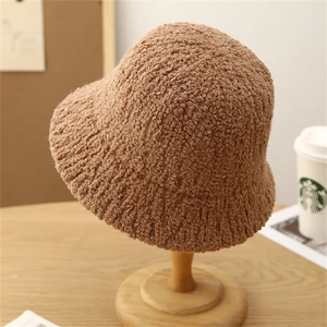 Caramel brown plush bucket hat in lambswool texture on a wooden stand for winter