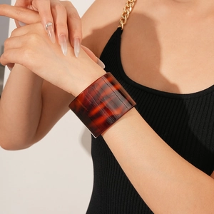 Close-up of a wide amber tortoiseshell acetate cuff bracelet with glossy leopard patterns