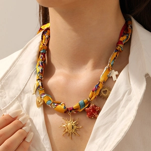 Detail of silk scarf necklace featuring sun, heart, and starfish metal pendants