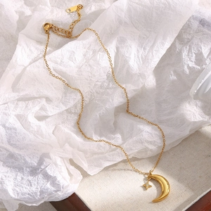 Detail shot of 18K gold plated moon and star pendant necklace on a textured tray