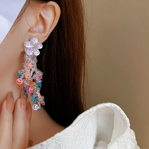 Détail de boucles d'oreilles à pampilles perlées avec fleurs sur un mannequin femme