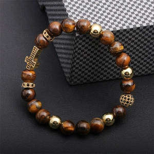Detail of tiger eye beads with gold cross charm and zircon spacer on a beaded bracelet