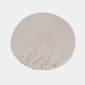 Dettaglio del basco in maglia beige con raffinati strass floreali e decorazioni di perle
