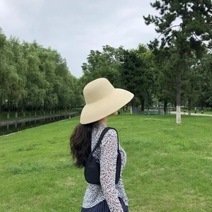 Outdoor lifestyle view of a woman wearing a black brim straw hat and leopard print shirt