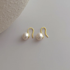 Detail of natural freshwater pearls on J-shaped golden ear hooks with a minimalist design
