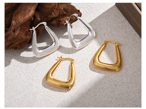Macro shot of geometric triangular matte metal earrings in gold and silver finishes