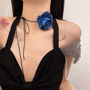 Detail of a dark blue fabric flower choker necklace with long black string tie on woman