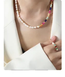 Detail of baroque pearl and colorful natural stone necklace on a white blazer model