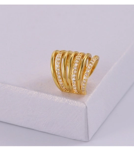 Detail of multi-layer gold ear cuff with zircon inlay on a white jewelry box edge