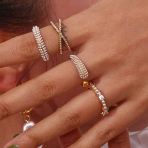 Detail shot of pearl and zircon gold rings on hand with multi-row and cross designs